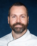 Derrick Connor wearing a chef coat and toque