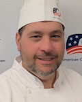 Carmelo Vadacchino wearing a chef coat and toque