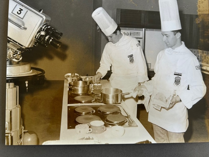 A couple of chefs cooking in a kitchen.